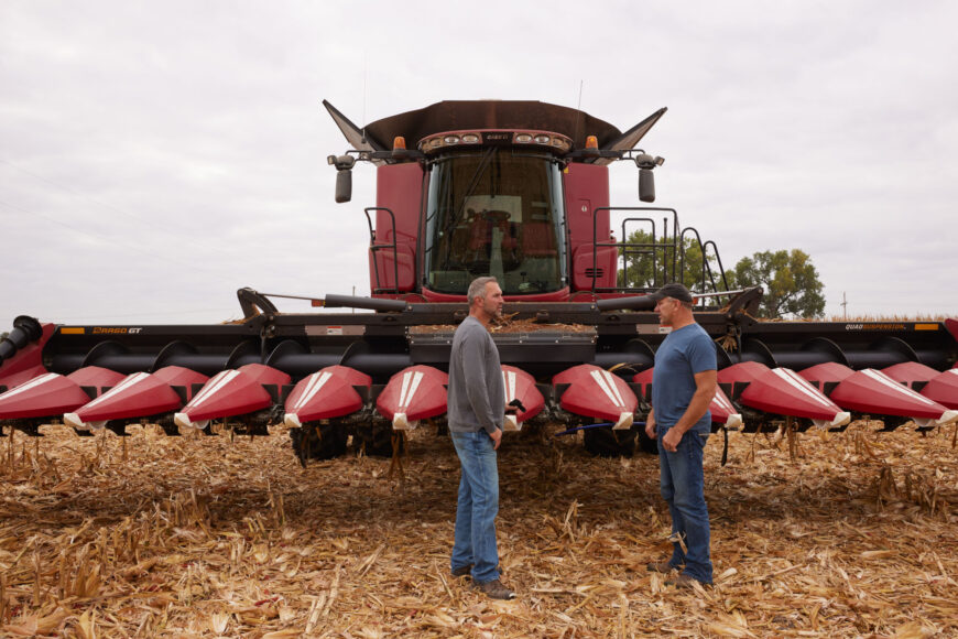Farmers talk near a combine at harvest.
