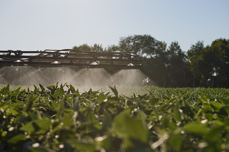 Spray boom applying herbicide to a soybean field.