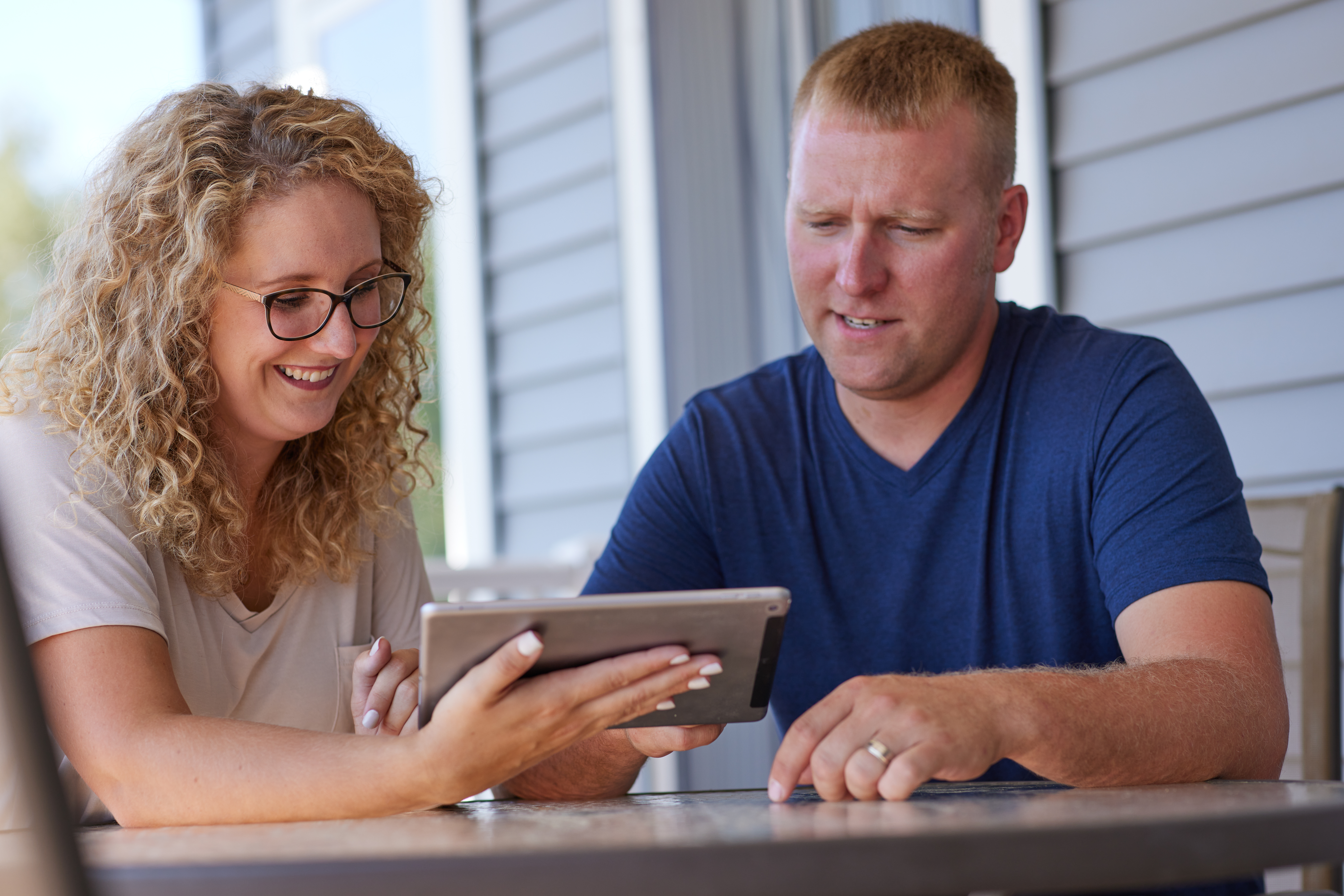 Man and woman sitting at a table reviewing data on tablet.