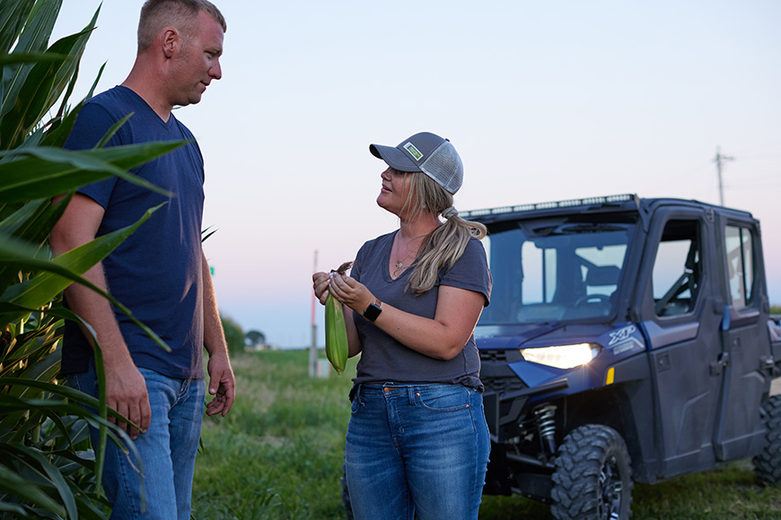 Grower and their advisor examine corn plants in a field.