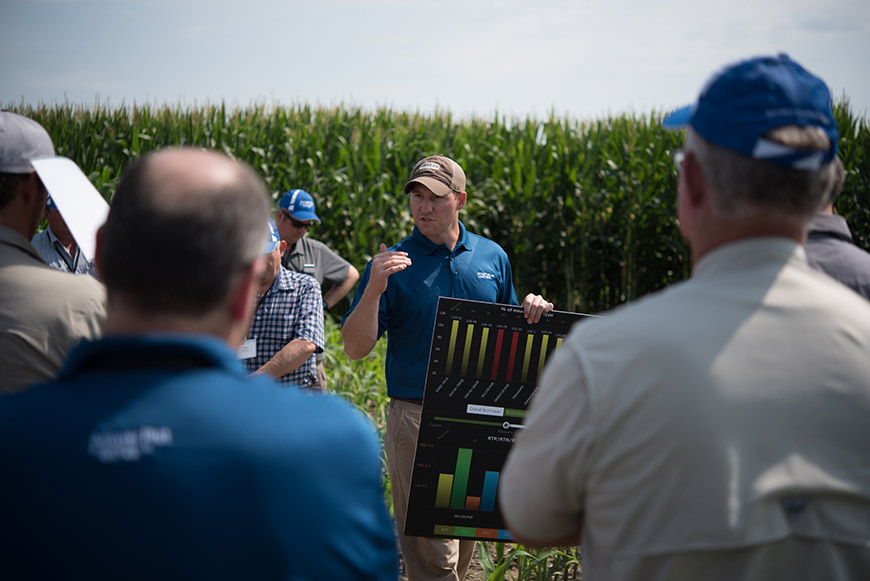 Men standing in cornfield discussing Answer Plot trial results