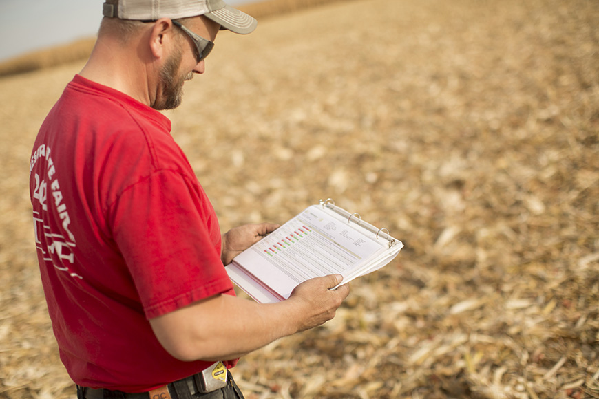 WinField United farmer evaluating nutrient reports in a harvested corn field.