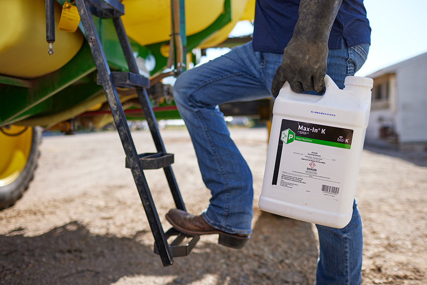 WinField United grower climbing into tractor holding MAX-IN K jug.