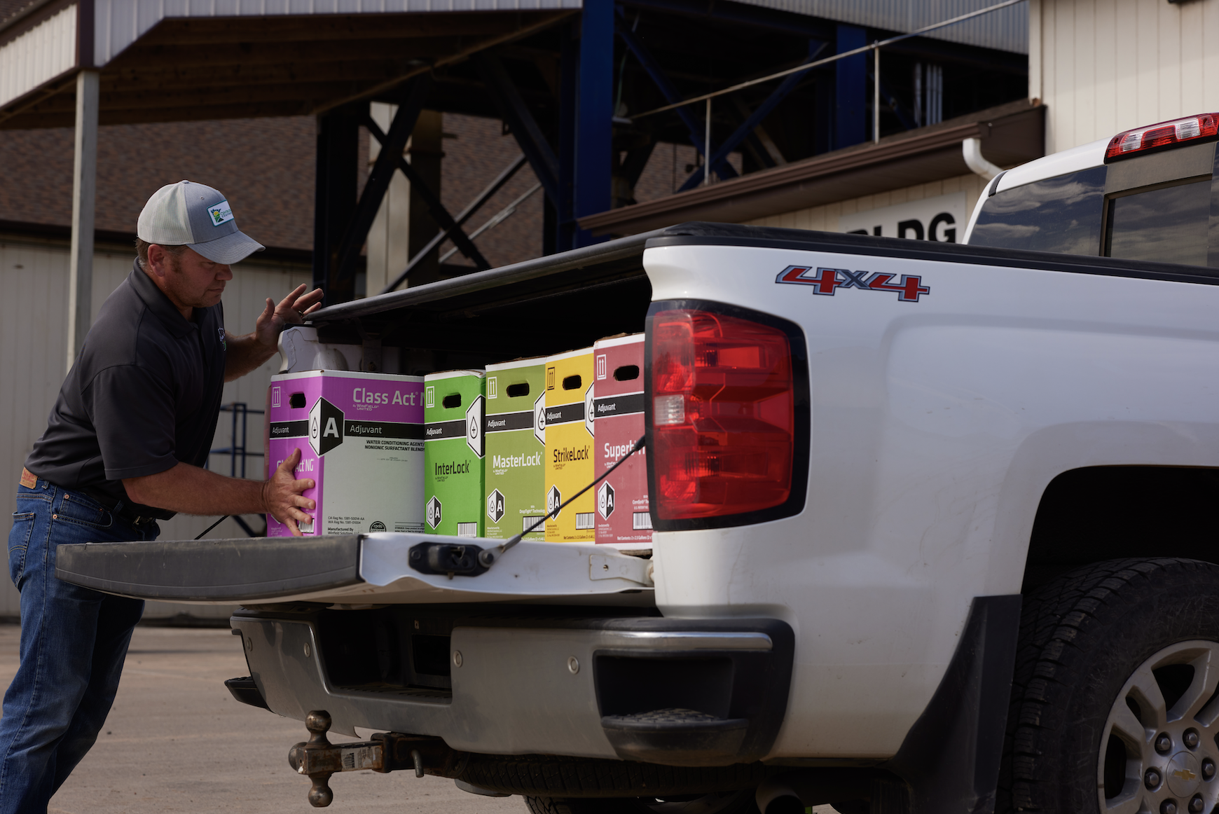 Retailer loading up boxes of adjuvants into the back of a pickup truck. 