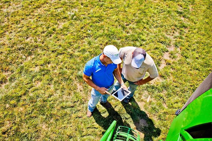 Two men reviewing a tablet discussing their season-long ag tech strategy